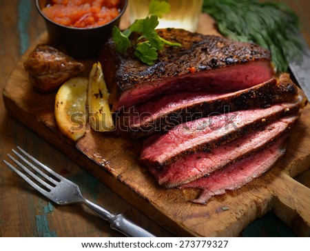 Steak with herbs and beer on a wooden background Royalty-Free Stock Photo #273779327