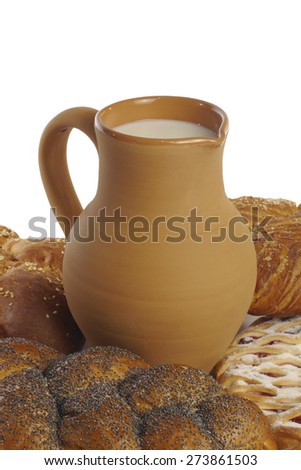 buns with poppy seeds and clay jug with milk on a white background