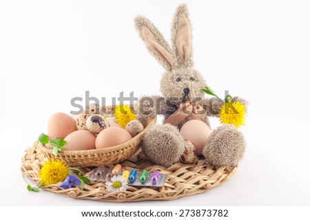 eggs in a basket, flowers and plush rabbit on a white background