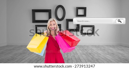 Stylish blonde in red dress holding shopping bags against big room with several frames at wall