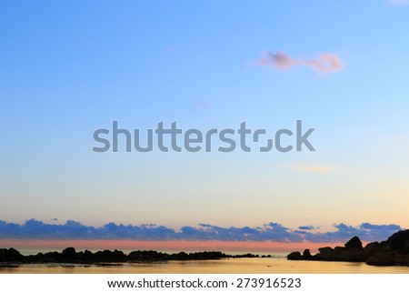 Brilliantly sunlit sky and clouds above calm surface of coastal waters in a secluded marine bay. Peacefulness, tranquility, remoteness, calm before the storm concept.  Royalty-Free Stock Photo #273916523