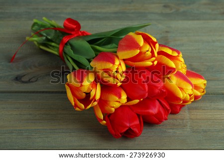 Bouquet of tulips with red ribbon on a wooden background