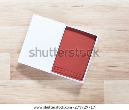 white paper box with brown envelopes inside on wooden background with shadow