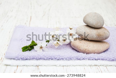 Cherry blossom, massage stone and towels on a wooden background