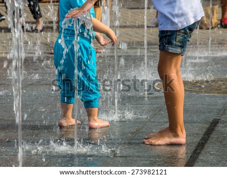 Kids playing in fountain with waterspouts coming from underneath, happy and curious Royalty-Free Stock Photo #273982121