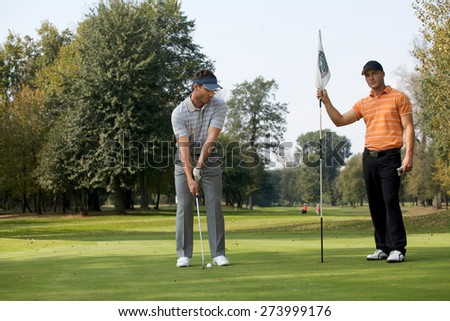 Portrait of young men standing with golf sticks on golf course