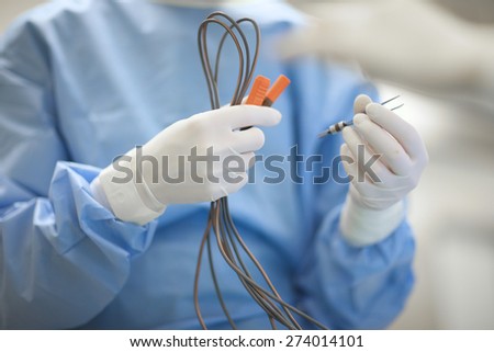 Surgeon's hands preparing coagulation wires for an operation Royalty-Free Stock Photo #274014101