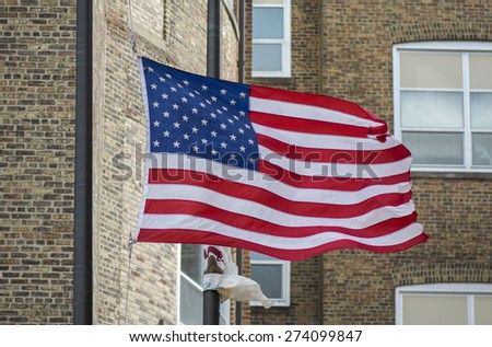 An American flag waving proudly in front of a tall brick building.