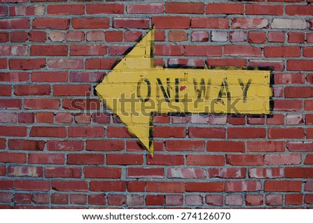 Red Brick Wall with Yellow One Way Arrow Sign Pointing Left