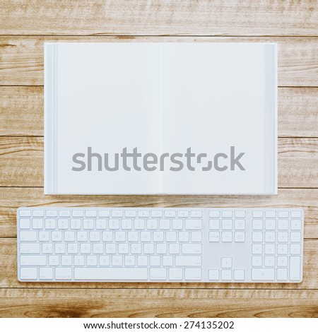 Conceptual picture: blank opened book and keyboard on wooden background.