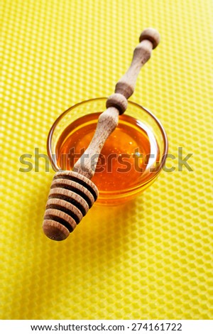 Honey and wooden dipper on honeycomb background