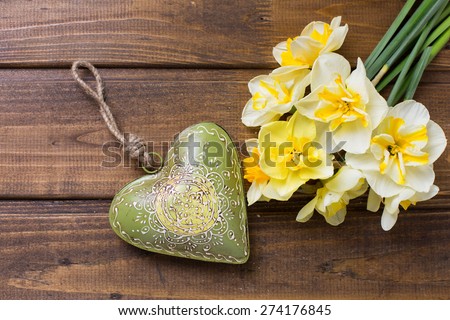 Fresh  spring yellow  daffodils  flowers and decorative heart  on brown painted wooden planks. Selective focus. Place for text. 