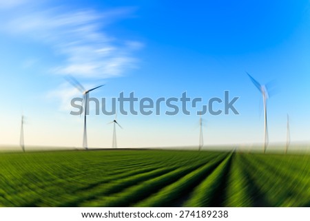 Radial blurred image. Windmills at sunset at a field of crops.