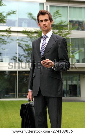 portrait of young confident caucasian businessman with cellphone