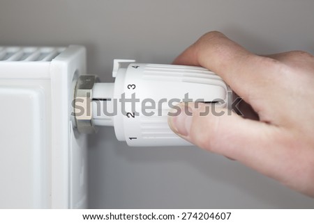 Closeup of man's hand adjusting thermostat at home Royalty-Free Stock Photo #274204607