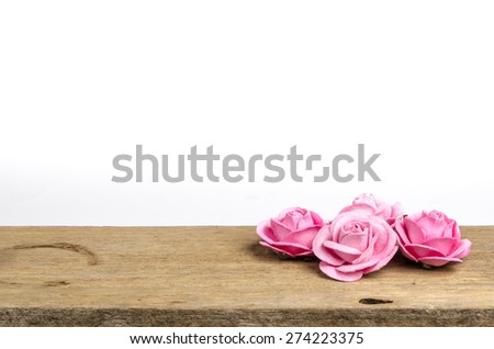 Artificial pink roses on old wood on white background