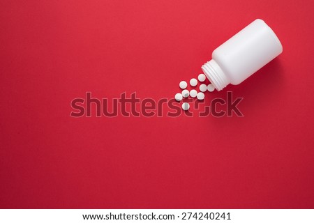 Pills spilling out of pill bottle and isolated on red. Top view with copy space. Medicine concept Royalty-Free Stock Photo #274240241