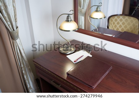 folder for notes and lamp standing on a table in a hotel room