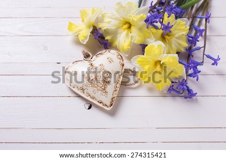 Bright  yellow and blue spring flowers and decorative heart  on white   painted wooden planks. Selective focus. Place for text.  