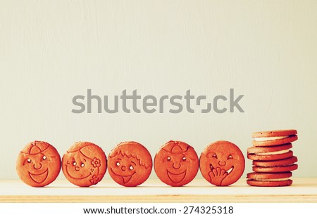 raw of cookies with smiley face over wooden table. image is retro style filtered 