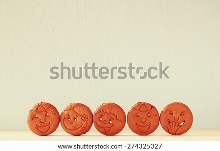 raw of cookies with smiley face over wooden table. image is retro style filtered 