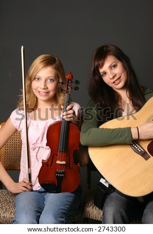 Teenage sisters with violin and guitar with dark background