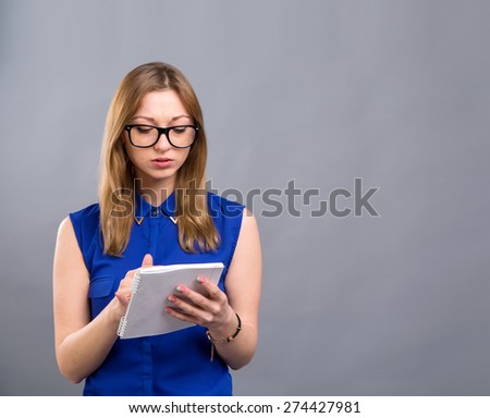 Young modern woman of European appearance holds a notebook to take notes. Woman wearing glasses. Girl student. Near person has space for text. Clever girl american. Education is good. Make report.