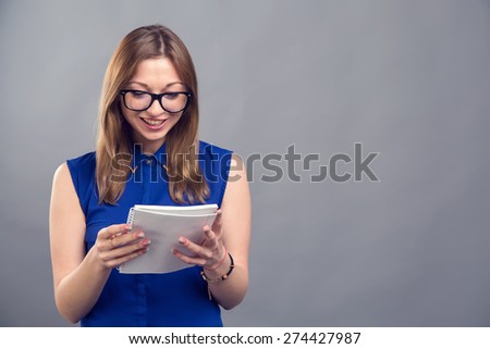 Young modern woman of European appearance holds a notebook to take notes. Woman wearing glasses. Girl student. Near person has space for text. Clever girl american. Education is good. Make report.