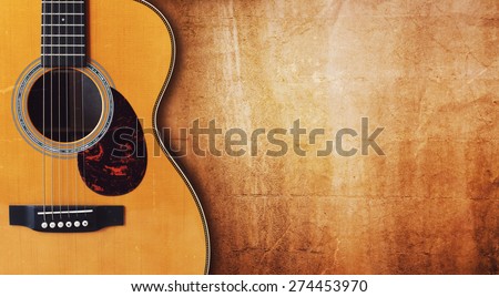 Acoustic guitar resting against a blank grunge background with copy space Royalty-Free Stock Photo #274453970