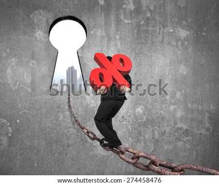Man carrying 3D red percentage sign walking on old iron chain toward keyhole door, with urban scene view and gray concrete wall background