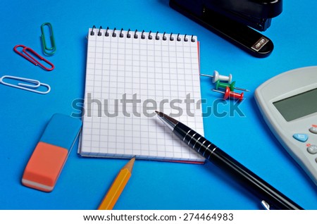 Notebook and office supplies on blue background