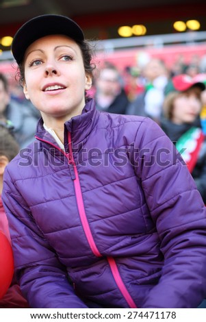 Young beautiful woman in a sports jacket and a cap at stadium