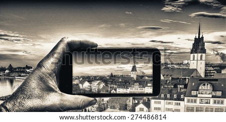Male hand with smartphone taking a picture of Friedrichshafen. Tourism concept.