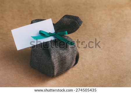 sack gift bag with ribbon bow on brown background- vintage effect style pictures
