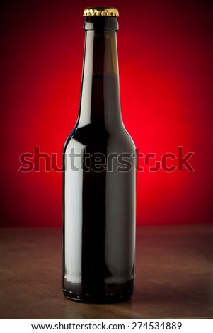 Bottle of beer on a stone table over red background