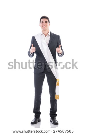 Young businessman confidently posing wearing winning ribbon or sash, showing thumbs up isolated in white background Royalty-Free Stock Photo #274589585