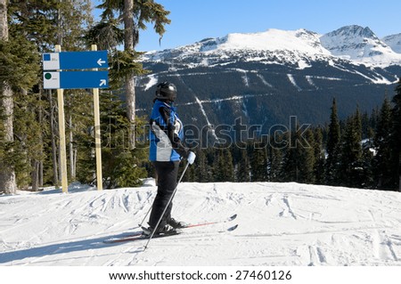 Female skier stopped on ski trail, looking at slopes and mountains ahead