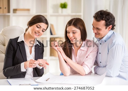 Young couple signing financial contract with female realtor.