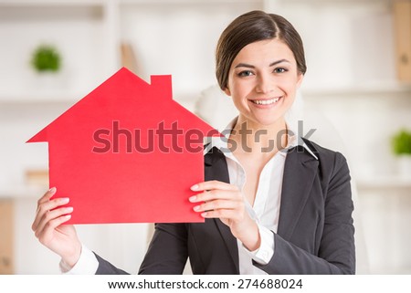 Happy realtor woman is showing home for sale sign.