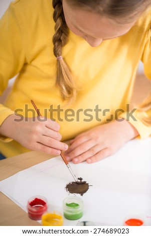 Little  girl in yellow  pullover making picture with  gouache paints.