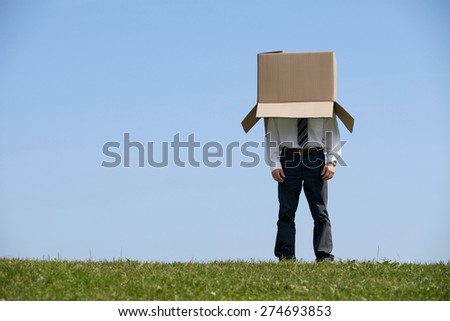 Man standing in park with cardboard box over his head