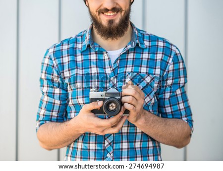 Young bearded man with vintage camera is making a picture.