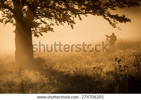 Silhouette of a young photographer during a foggy sunrise.