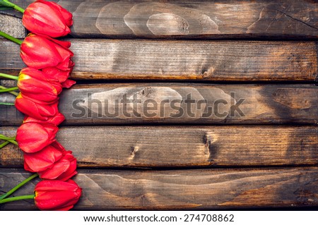 Tulips. Red tulips on a background of dark boards. Spring flowers. Springtime. Vintage processing. Space for text.