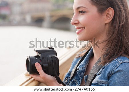 Beautiful happy young brunette taking photographs.