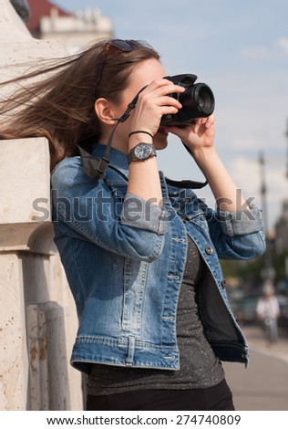Beautiful happy young brunette taking photographs.