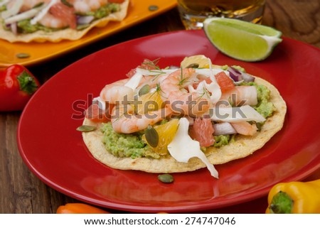 Two plates of shrimp ceviche tostadas with fennel and grapefruit, beer, garnished with mini bell pepper.
