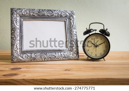 Still life with vintage clock and photo frames on wooden table over grunge background