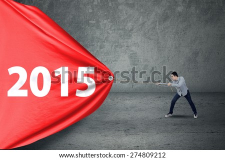 Person pulling number 2015 on a big banner, symbolizing a change in future