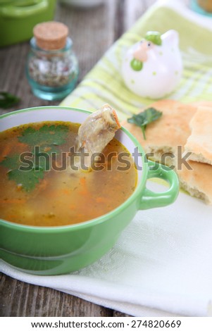Chicken soup in green bowl on a wooden table